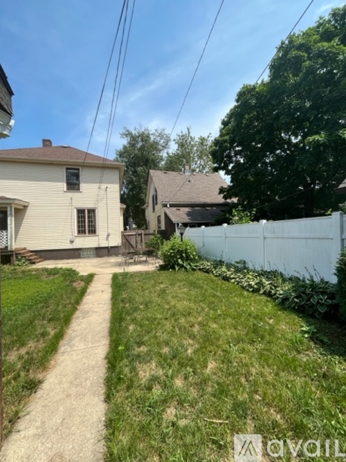 A white fence separates a grassy area from a house.