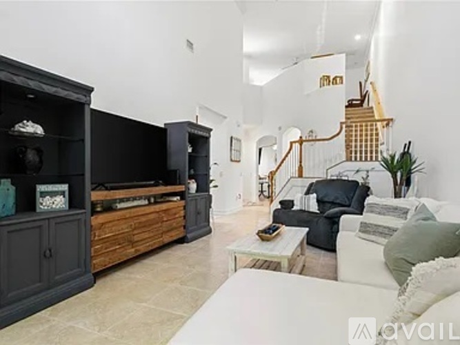 A living room with a white couch and a wooden entertainment center.