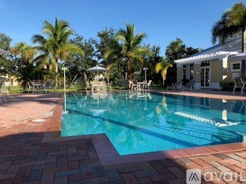 A pool surrounded by palm trees and a gazebo.