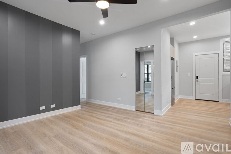 A spacious room with wooden flooring and a ceiling fan.