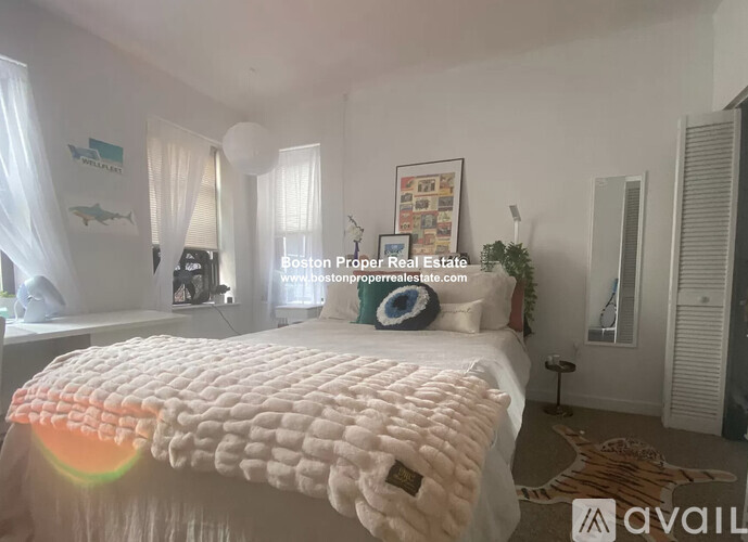 A bedroom with a large bed and a window with curtains.