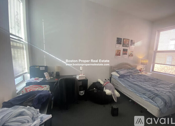 A bedroom with a bed, desk, and window.