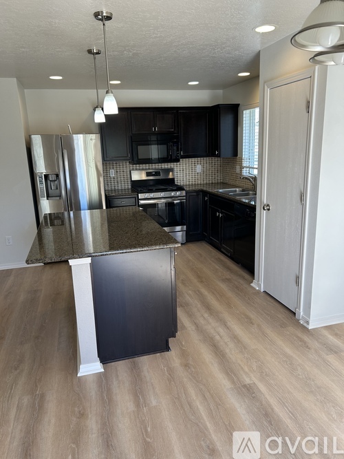 A kitchen with black cabinets and a granite countertop.