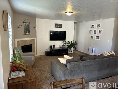 A living room with a grey couch, a wooden coffee table, and a flat screen TV mounted on the wall.