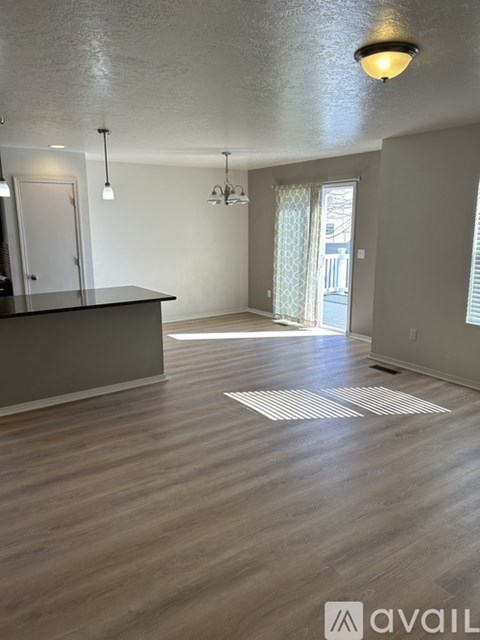 A spacious room with wooden flooring and a bar area.