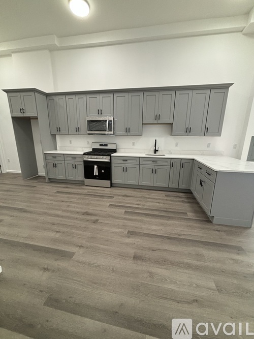 A kitchen with grey cabinets and a wooden floor.