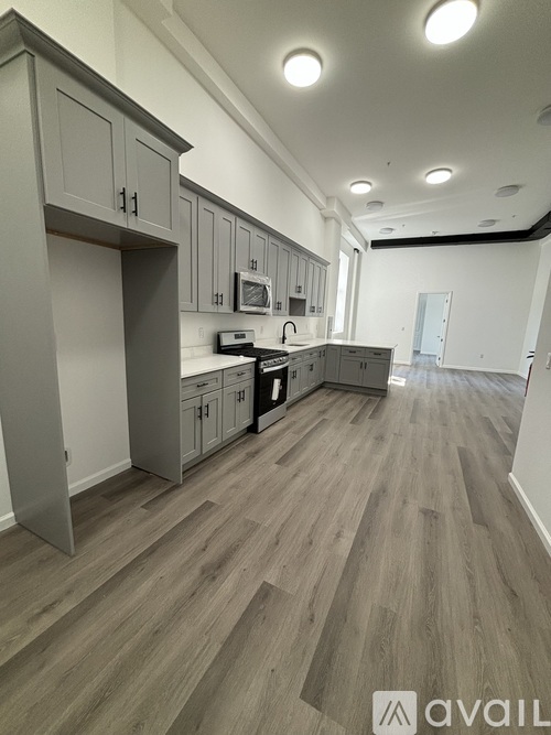 A kitchen with wooden floors and grey cabinets.