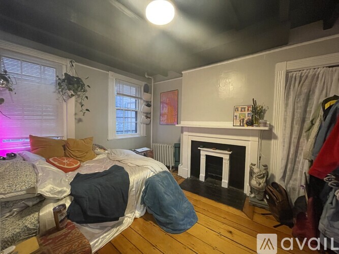 A bedroom with a bed, a fireplace, and a window.