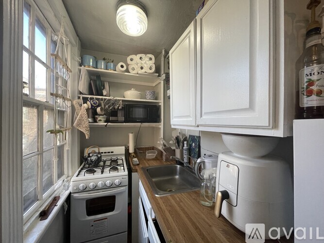 A small, cluttered kitchen with a white stove, sink, and cabinets.