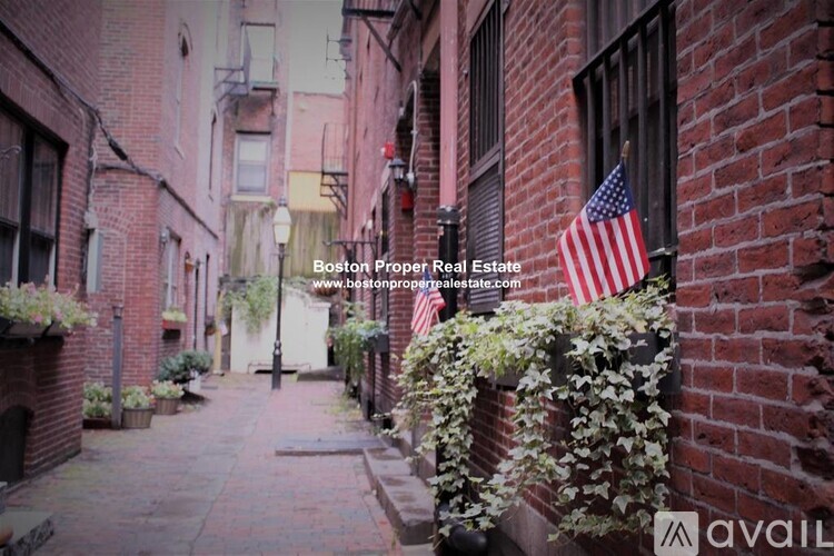 A narrow alley with brick buildings and a flag on the right.