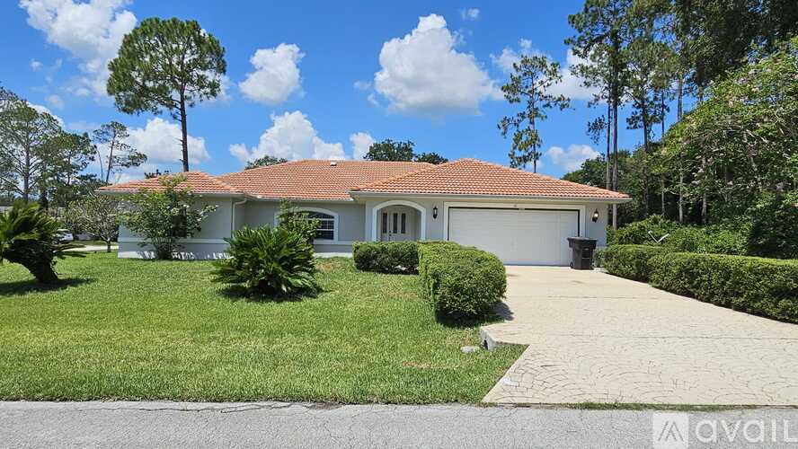 A house with a red tiled roof and a driveway in front.