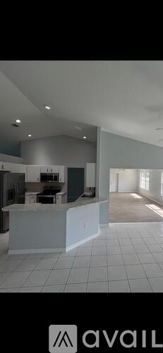 A spacious kitchen with white tiled floors and a large island in the center.