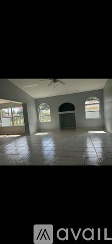 A spacious room with a fan and arched windows.