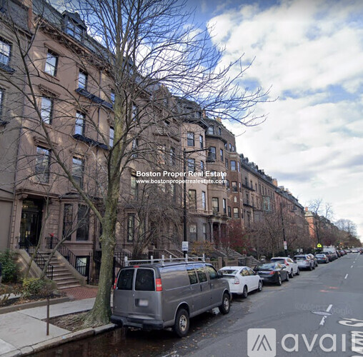 A street view of a row of brown buildings with cars parked on the side.