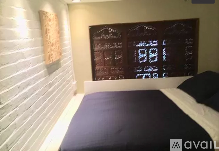 A bedroom with a bed, pillow, and a wooden wall.