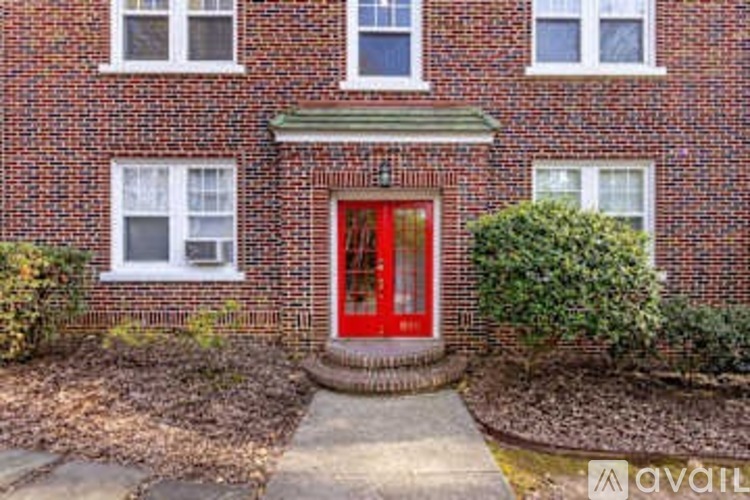 A red door is the centerpiece of this brick building.