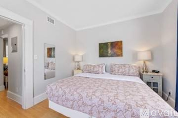A bedroom with a large bed and two lamps.