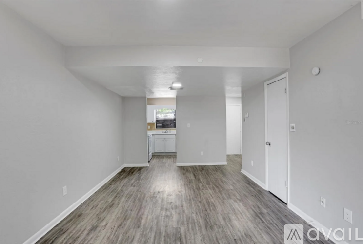 A spacious room with wood flooring and white walls.