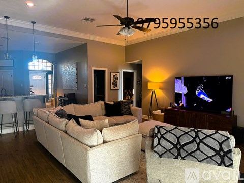 A living room with a beige couch and a television on a wooden stand.