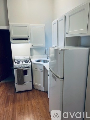 A kitchen with a white fridge, stove and sink.