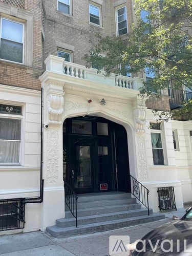 A white building with a black door and a balcony with a metal railing.