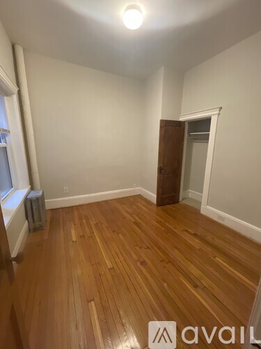A room with wooden flooring and a door on the right side.