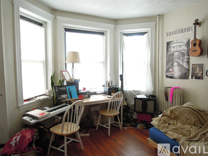 A room with a desk, chair, and guitar hanging on the wall.