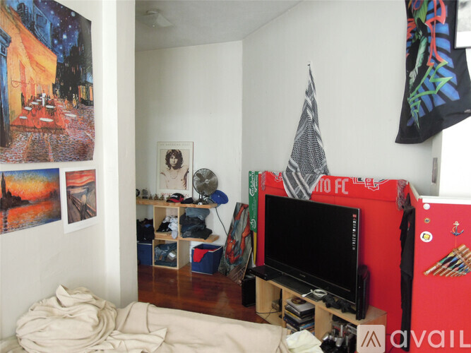 A room with a red TV stand and a white wall with a painting on it.