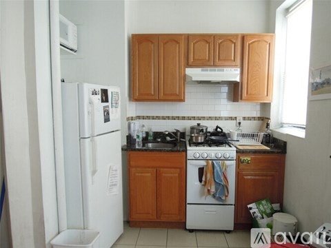 A kitchen with a white fridge, white stove and wooden cabinets.