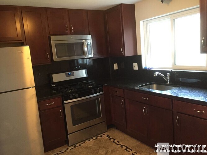A kitchen with dark wood cabinets and stainless steel appliances.