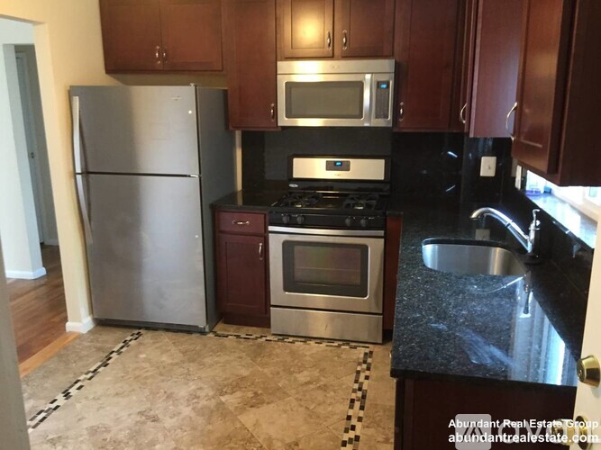 A kitchen with a refrigerator, oven, microwave, and sink.