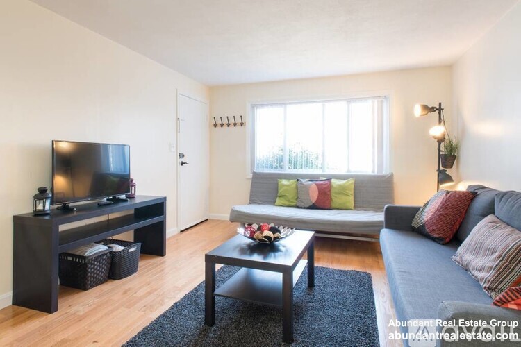 A living room with a grey couch, a black coffee table, and a television on a stand.