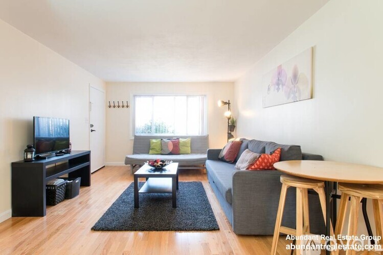 A living room with a grey couch, a black entertainment center, and a wooden coffee table.