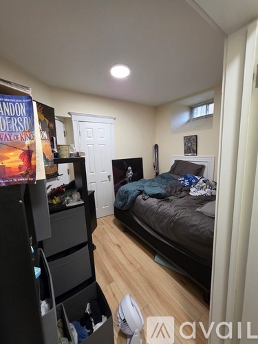 A bedroom with a bed, dresser, and a poster of a book.