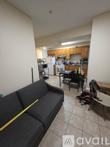 A living room with a grey couch and a kitchen in the background.
