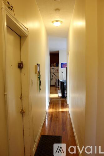 A hallway with a mat on the floor and a door on the left.