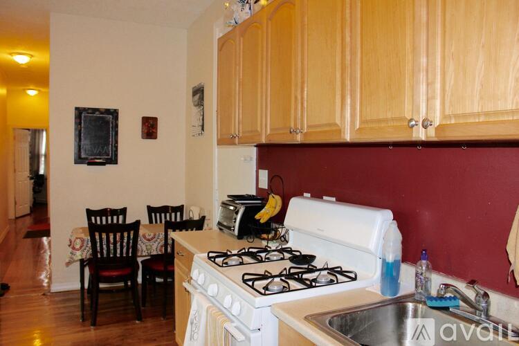 A kitchen with a stove, sink, and chairs.