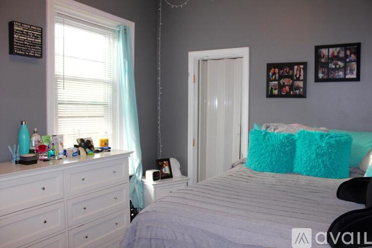 A bedroom with a white bed and a white dresser with a mirror above it.
