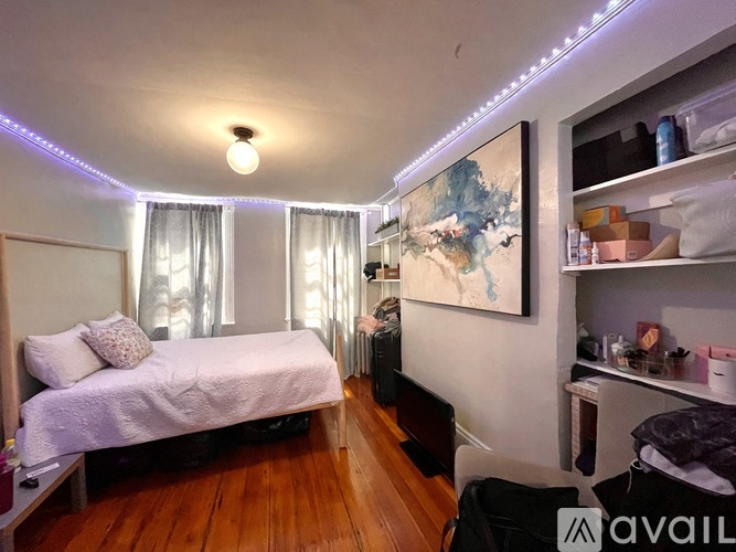 A bedroom with a bed, a shelf, and a painting on the wall.