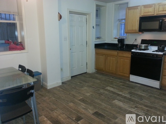 A kitchen with a black counter top and wooden floors.