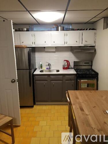 A kitchen with wooden flooring and a wooden table in the foreground.