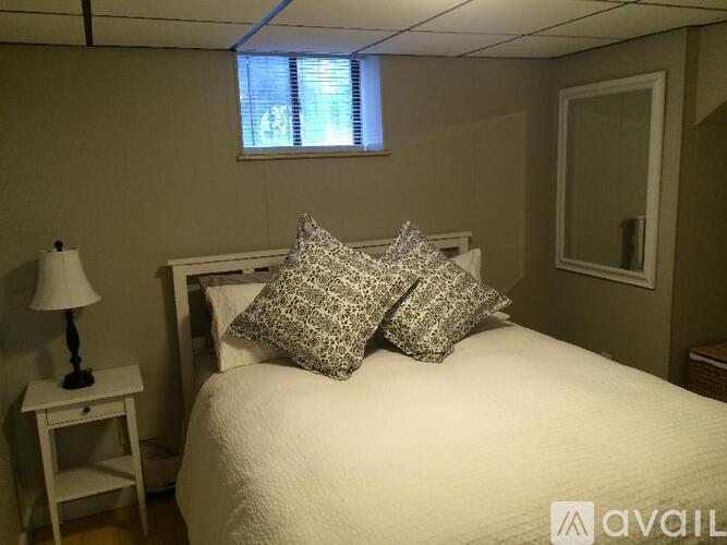 A bedroom with a bed, a nightstand with a lamp, and a window with blinds.