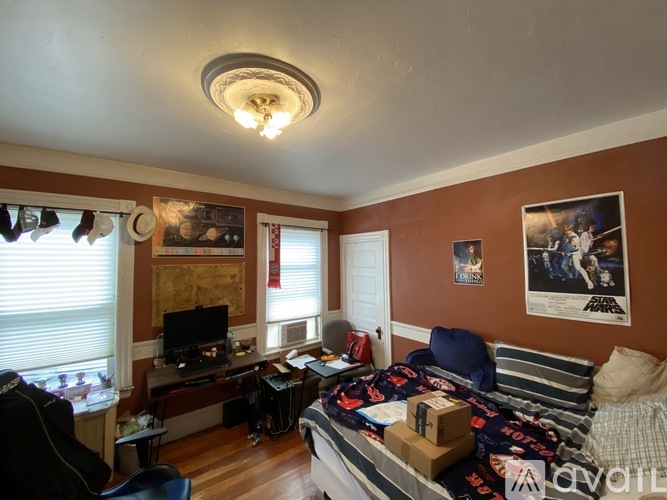 A room with a bed, a desk with a computer, and a chair.