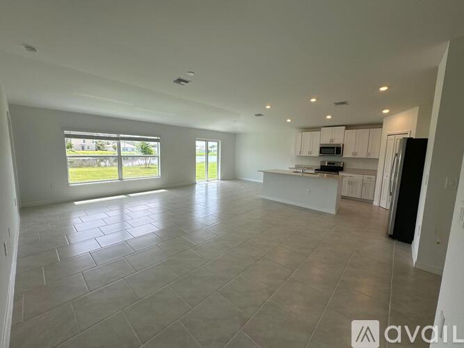 A spacious, empty living room with tiled flooring and large windows.