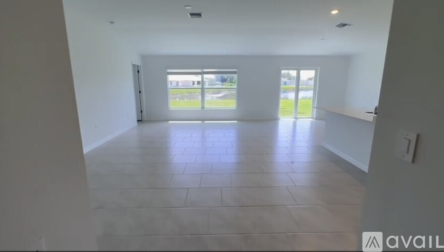 A spacious room with tiled flooring and large windows.