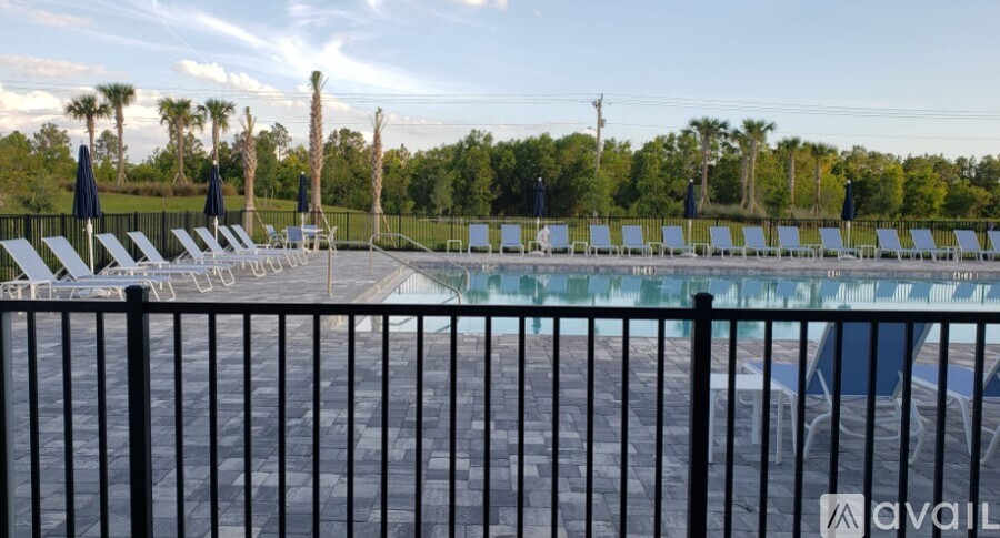 A pool surrounded by a fence and chairs.