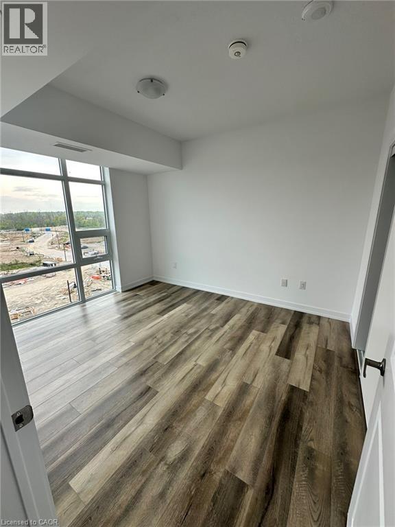 A room with wooden flooring and a large window overlooking a construction site.