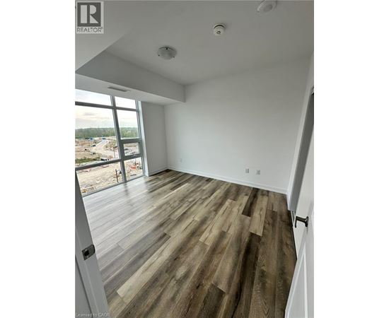 A room with wooden flooring and a large window overlooking a construction site.
