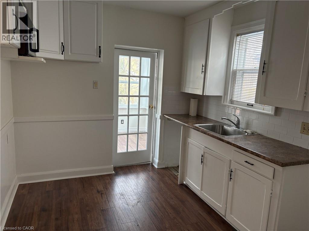 A kitchen with white cabinets and a wooden floor.