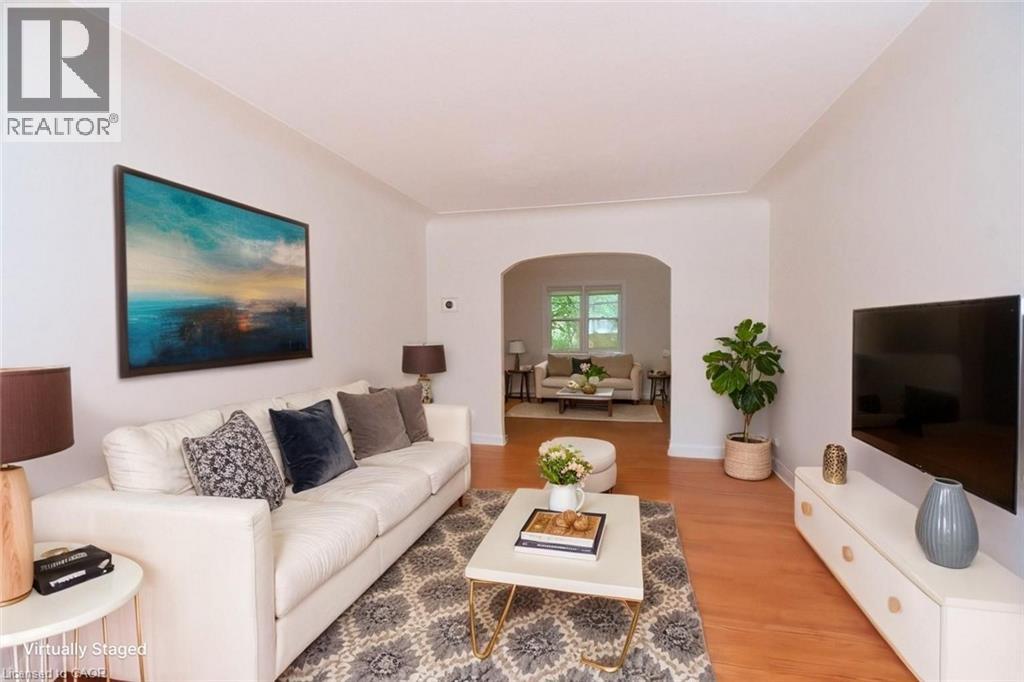 A living room with a white couch and a painting on the wall.